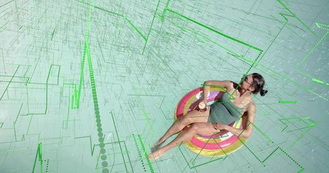 Asian woman floating on colorful ring in neon digital grid — futuristic summer relaxation
