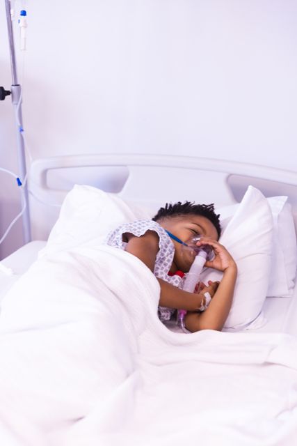 Vertical of african american boy patient wearing ventilator, asleep in hospital bed, with copy space. Medical services, hospital and healthcare concept.