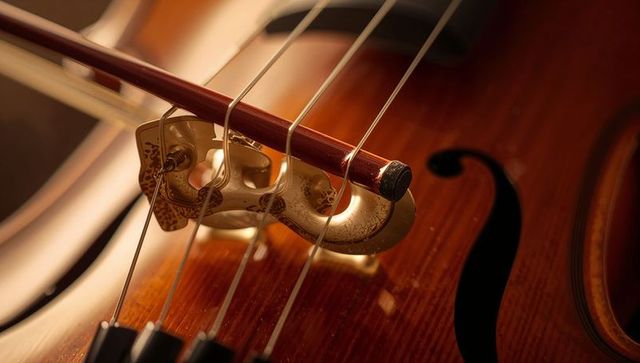 Close up on cello strings with bow in warm studio light