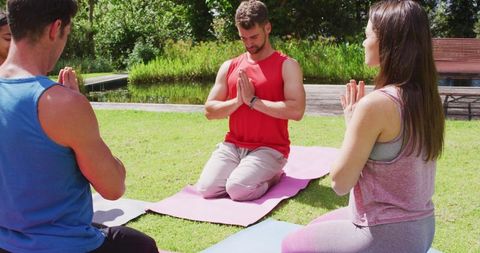 Group Practicing Yoga Kneeling Pose Outdoors in Sunny Park