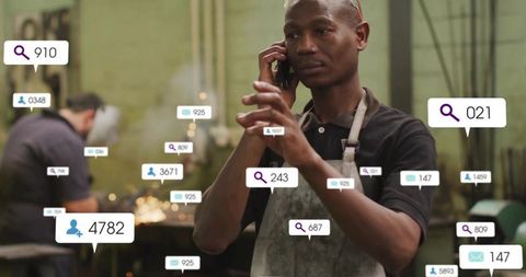 Factory worker talking on phone in metal workshop with analytics overlays and grinding sparks