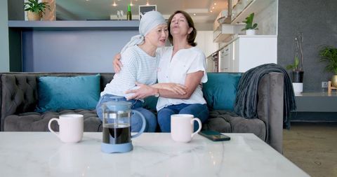 Senior Friends Embracing and Bonding Over Coffee at Home