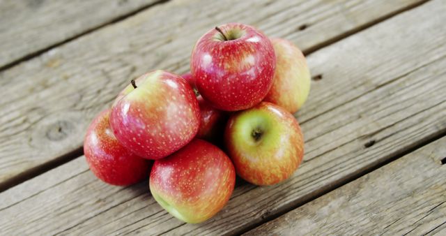 A pile of ripe red apples sits on a wooden surface, with copy space. Fresh fruit like these apples is often associated with healthy eating and autumn harvests.