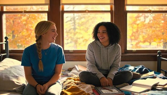 Sunlit autumn bedroom friends chatting on bed studying and laughing during cozy afternoon