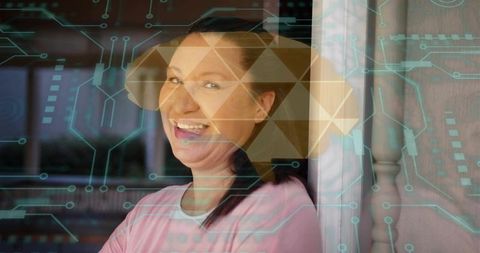 Smiling woman leaning on porch doorway wearing pink top with golden hexagon tech overlay