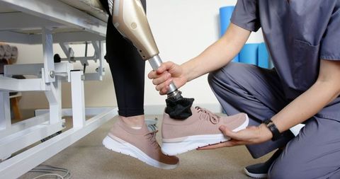 Healthcare professional adjusting prosthetic leg for patient
