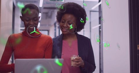 Colleagues examining laptop with ar icons in modern office environment