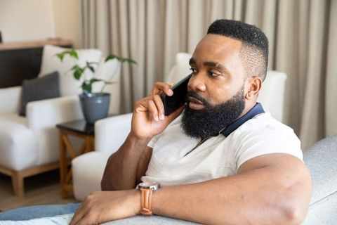 Man relaxing at home while communicating on smartphone