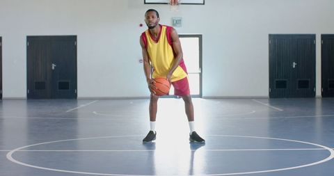 Focused Basketball Player Practicing Dribbling in Indoor Court