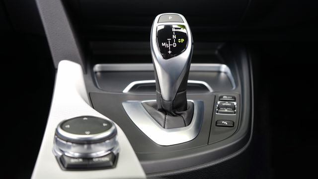 Close-up of gear shift knob and control panel in luxury car, highlighting modern, sleek design and advanced technology. Can be used in automotive industry content, vehicle reviews, blog posts about car technology, and advertisements promoting luxury cars.