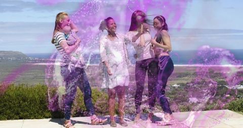 Smiling women holding baby on coastal terrace enjoying summer with violet sparkles