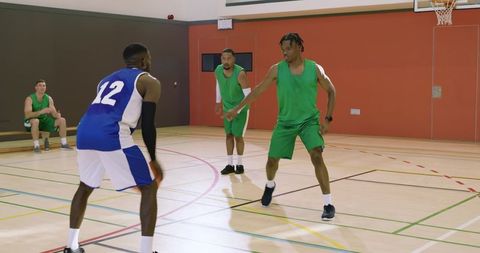 Diverse basketball players defending inbound pass and dribbling on indoor court