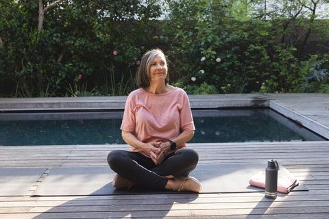 Senior woman meditating outdoors by pool