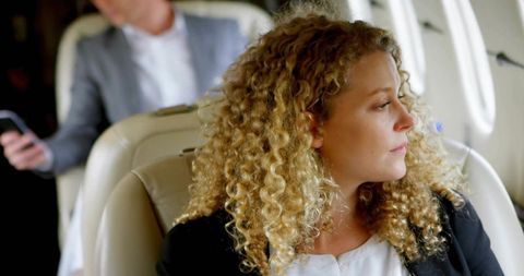 Curly businesswoman gazing out private jet window, luxury corporate travel and entrepreneurship