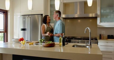 Senior couple preparing fresh vegetables in modern kitchen