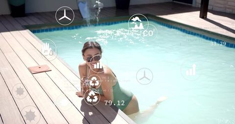 Young woman lounging on pool deck in green swimsuit wearing sunglasses with tech overlays