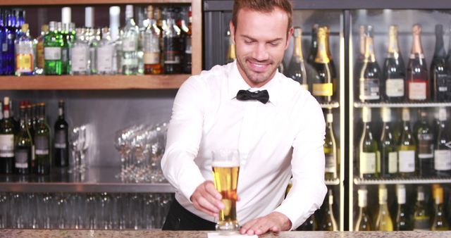 Smiling barkeeper serving a beer at bar