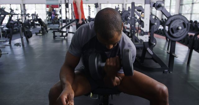 Young African American man lifting weights at the gym. His focused workout routine exemplifies dedication to fitness.