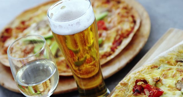 Slices of pizza alongside a glass of beer and wine on a table. Ideal for restaurant advertisements, blog posts about dining experiences, or content related to Italian cuisine.