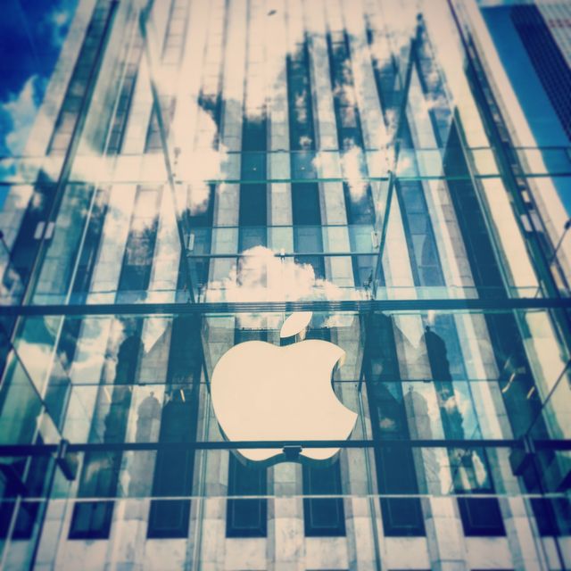 Modern architecture of an Apple Store showcases its corporate logo on glass windows. Designed for technology and retail-related uses, useful for articles on corporate branding, technology trends, modern retail spaces, or architectural photography.