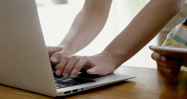 Hands Typing on Laptop with Phone Nearby at Wooden Desk - Download Free Stock Images Pikwizard.com