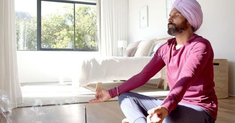 Man meditating in sunlit bedroom for mindfulness and inner peace