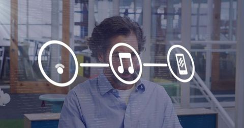 Man typing at office desk with floating music, wifi and smartphone interface icons