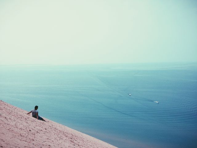 Man Relaxing on Sand Dune Overlooking Tranquil Sea - Download Free Stock Photos Pikwizard.com