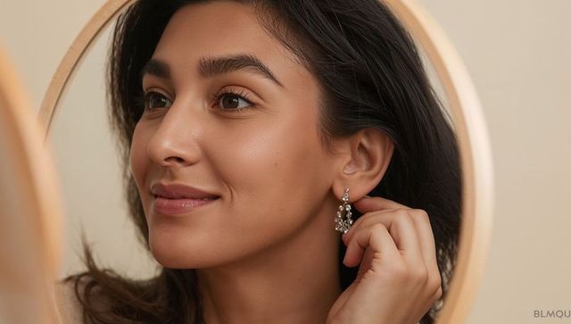 Adjusting multi-stone earring while gazing into round mirror closeup beauty portrait
