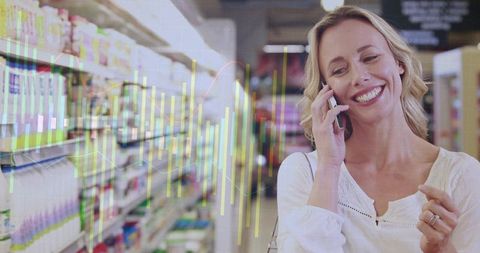Happy shopper smiling while talking on smartphone in grocery aisle with data overlay