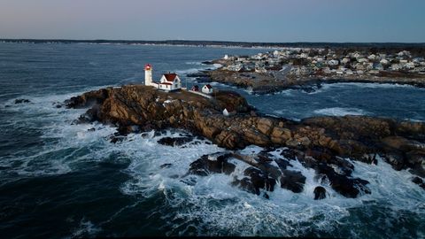Coastal lighthouse on rugged cliffside overlooking ocean at sunset