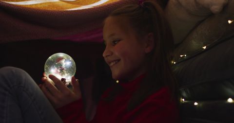 Girl Enjoying Magical Moment with Snow Globe During Christmas