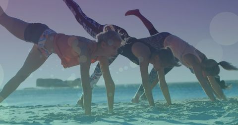 Female Friends Practicing Yoga on Beach at Sunset
