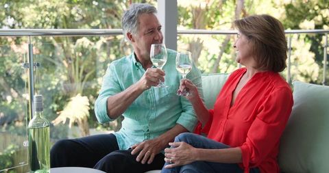 Senior Couple Relaxing on Balcony with Wine, Smiling at Each Other