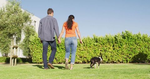 Romantic Couple Walking Dog in Sunny Green Park