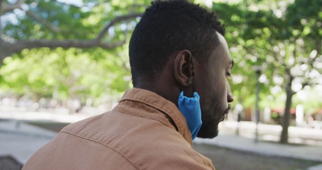 Man Relaxing in Outdoor Park with Mask on Ear - Download Free Stock Images Pikwizard.com