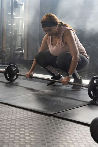African american woman bracing barbell before heavy squat training session in urban gym