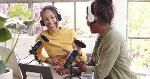 Diverse female co-hosts recording podcast at bright studio