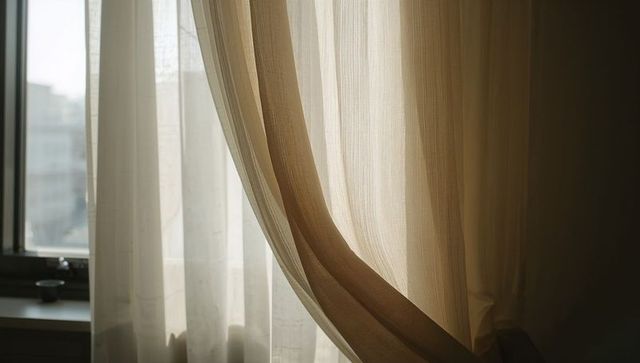 Sunlit sheer curtains filtering soft morning light through window