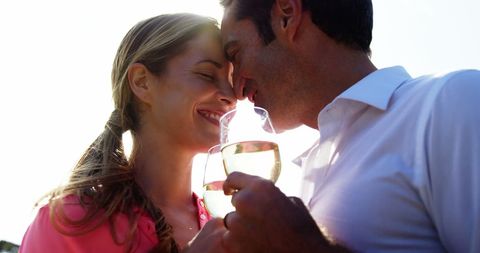 Romantic Couple Enjoying Wine Together in Sunlit Field