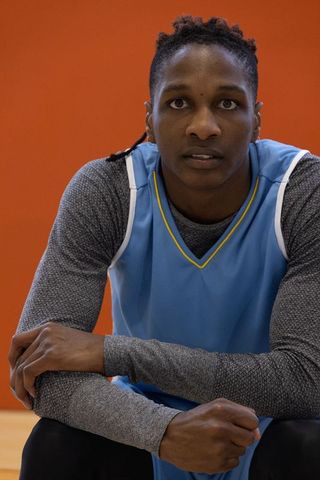 Athlete crouching in basketball jersey shows determination in gym