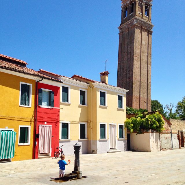 Child Playing Near Colorful Houses with Bell Tower in Background - Download Free Stock Images Pikwizard.com