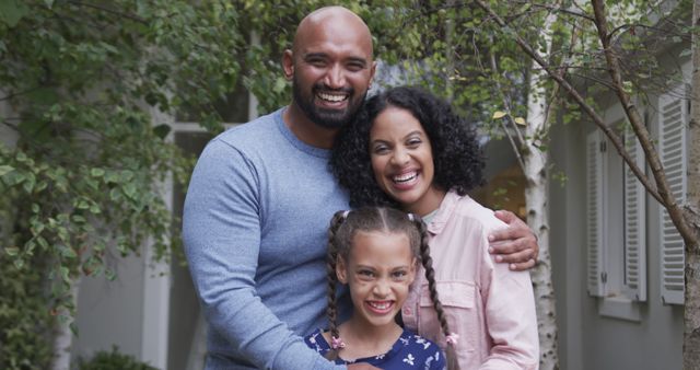 Portrait of happy biracial parents with daughter in garden. Family, togetherness, lifestyle, and domestic life, unaltered.