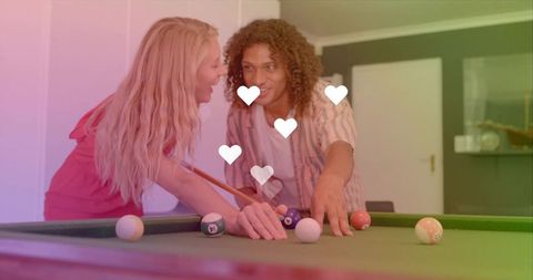 Couple leaning over pool table sharing playful romantic moment with hearts overlay