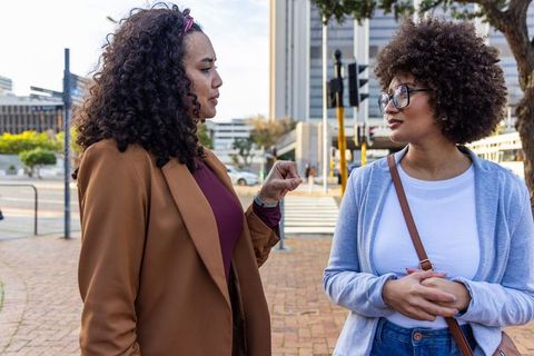 Diverse women talking on city corner during casual urban conversation and friendship
