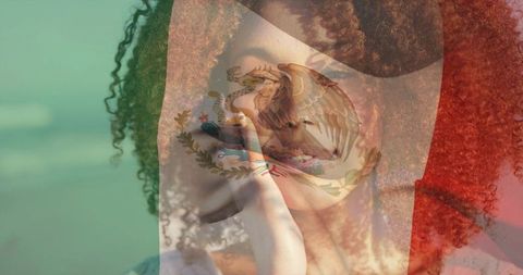Young woman holding chin seaside with translucent mexican flag double exposure