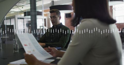 Coworkers Discussing Reports in Modern Office with Graph Overlay