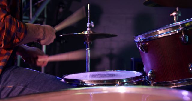 Midsection of caucasian male drummer playing drums at band practice. Music, practice, creativity and lifestyle, unaltered.