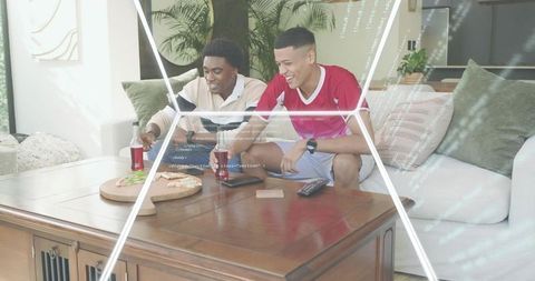 Friends reaching for pizza on sunlit sofa sharing drinks and casual weekend game night fun