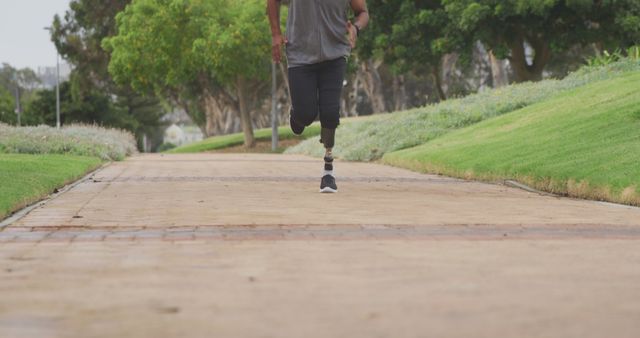 Biracial man running with his prosthetic leg alone in park. Sport, active lifestyle and disability.
